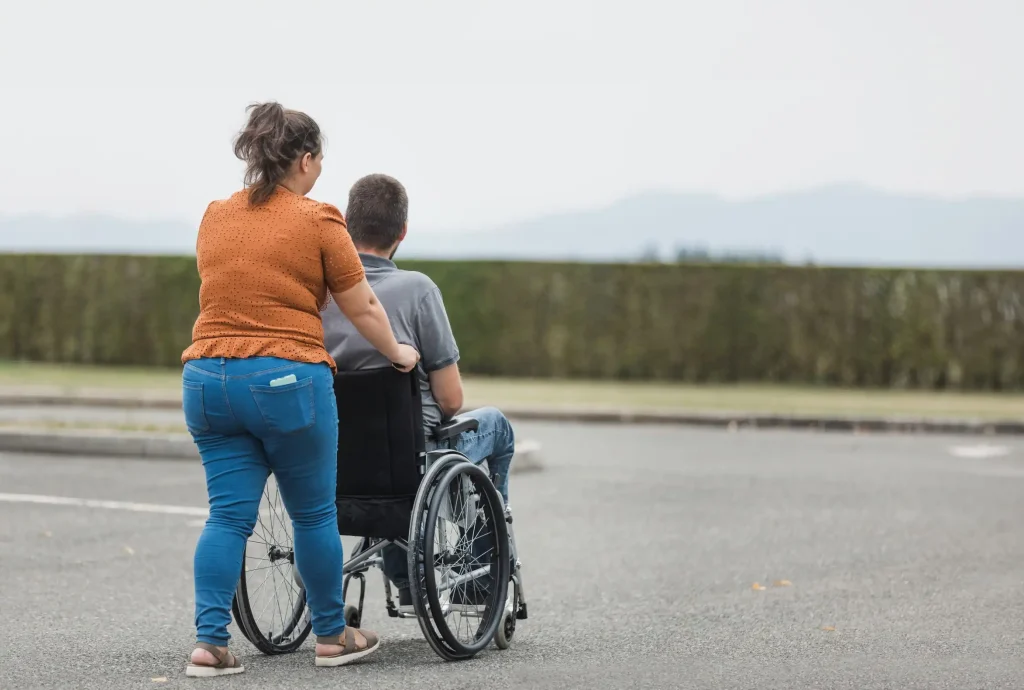 Disabled man in wheelchair being pushed by support worker